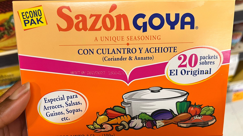 Hand holding a package of Goya Sazón in a store