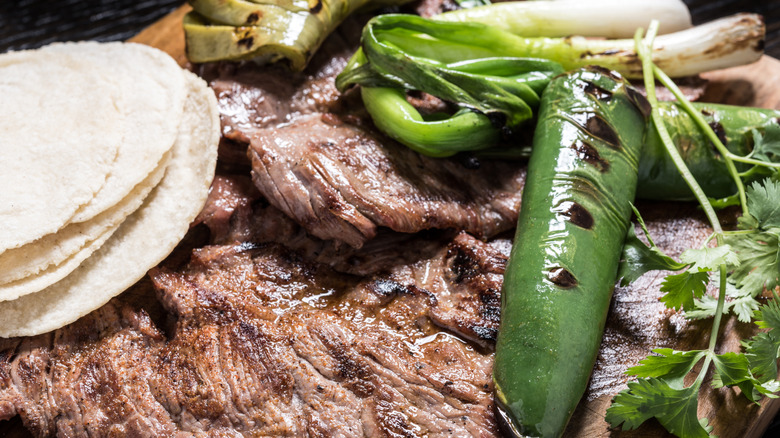 Mexican carne asada with tortillas, roasted jalapeños, cilantro and grilled green onions