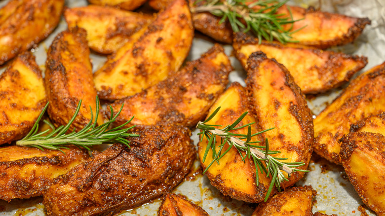 Perfectly baked potato wedges with crispy golden edges garnished with rosemary sprigs