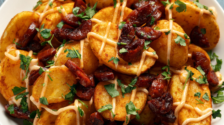 Patatas with chorizo and sauce on a white plate