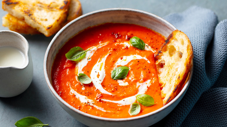 A bowl of roasted red pepper with toast and creamer of milk on side