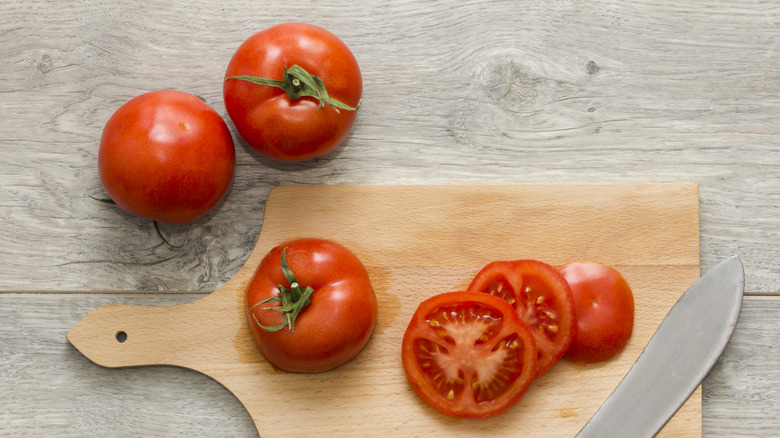Sliced tomatoes and a knife on a wooden cutting board
