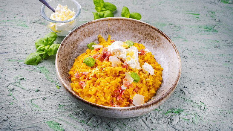 Risotto in a bowl topped with slices of ham and fresh cheese