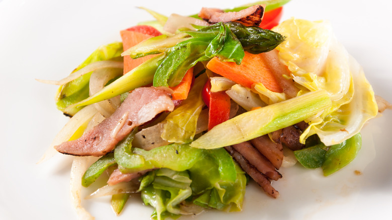 Sautéed colorful vegetables mixed with pieces of deli meat on a plate