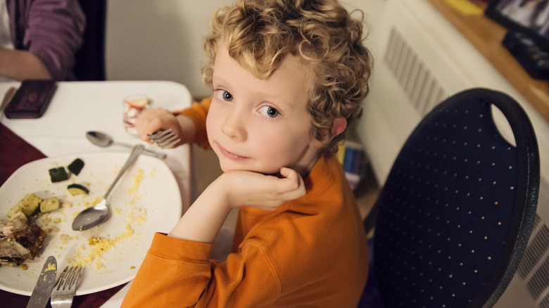 Young child eating a big dinner, 1980s