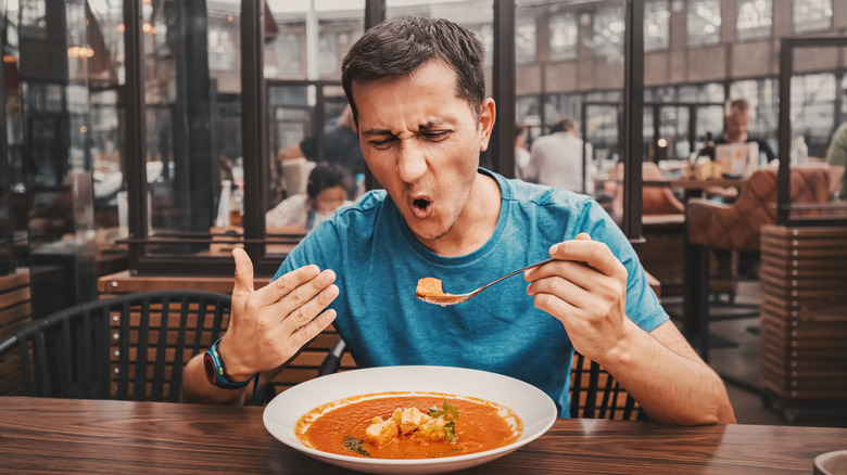 Man reacting to eating a spicy soup