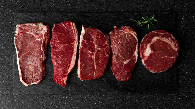 Different cuts of steak on black background