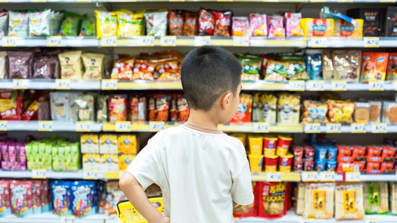 A young boy looking at the the snack and candy aisle in a grocery store