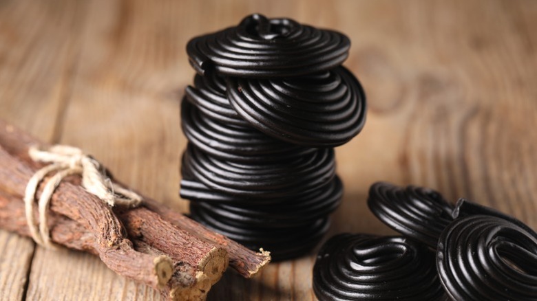Licorice candies next to a bundle of the licorice root.