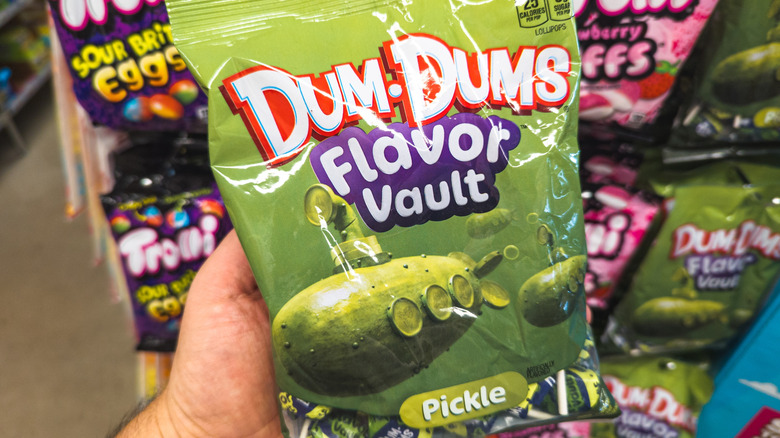 Someone holding a bag of Dum Dums Flavor Vault candy Pickle flavor.