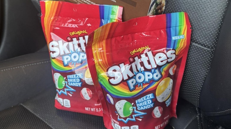 Two bags of Skittles Pop'd on a car seat.