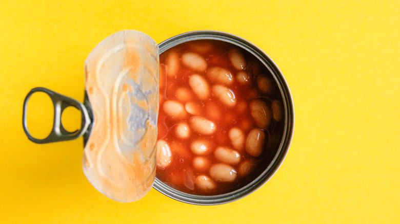 baked bean can slightly ajar on yellow background