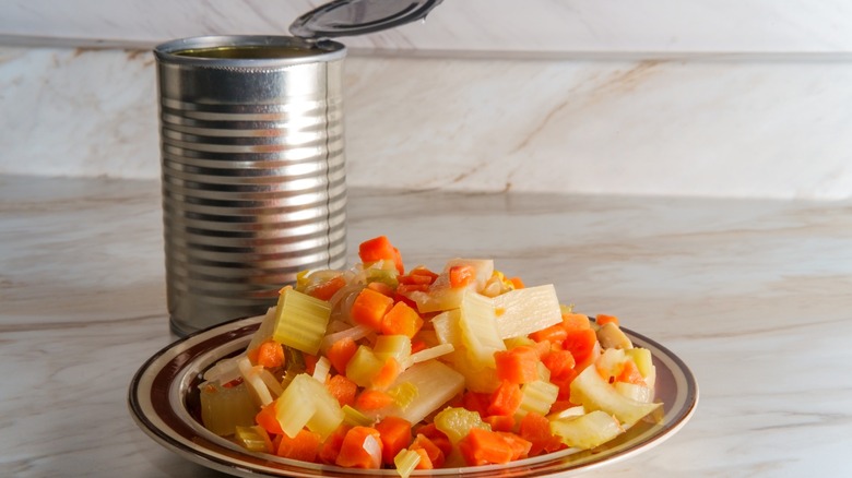 canned mixed veggies on white plate by steel can