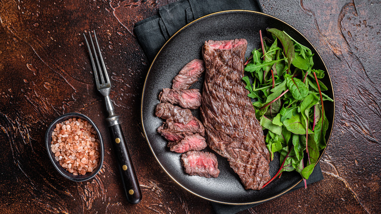Grilled steak cooked to medium on plate with salad and salt