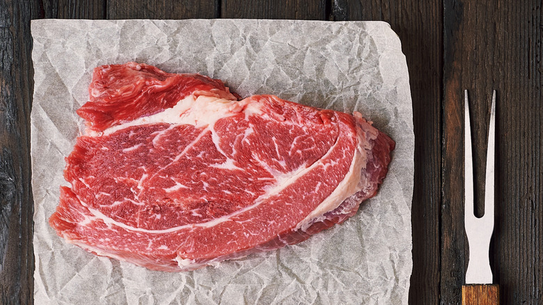 Raw steak sitting out on a wooden table