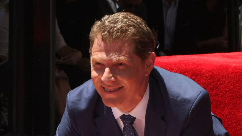 Bobby Flay smiles in a suit and tie