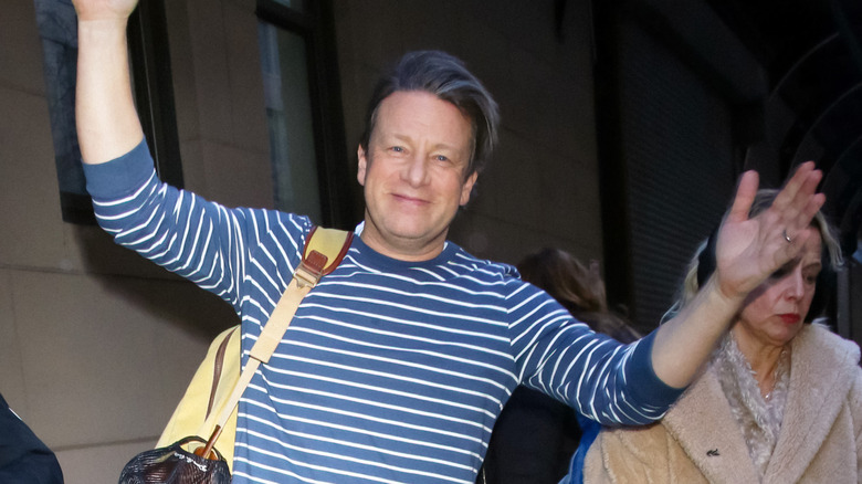 Jamie Oliver with a closed lip smile and wearing a blue and white striped shirt