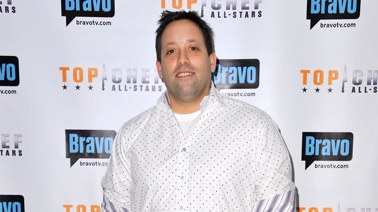A smiling Mike Isabella against a Top-Chef All-Stars backdrop