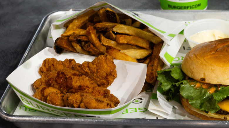 A BurgerFi meal meal of chicken tenders, a burger, and fries on a tray