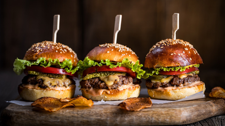 Three burger sliders on a wooden board