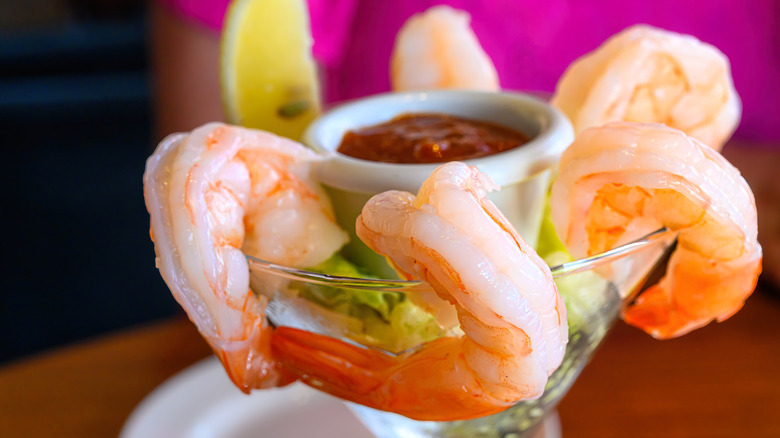 A martini glass filled with fresh shrimp and a cocktail sauce