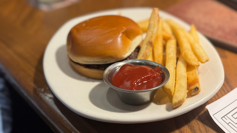 Outback Steakhouse burger and fries kids meal on a white plate on a wooden table