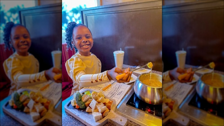 Little girl in a booth smiling and dipping a skewer in melted sauce at Melting Pot