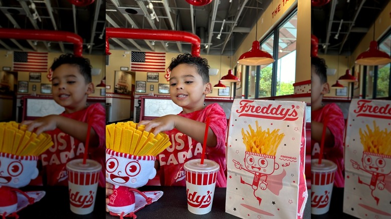 A child playing with Freddy's kids meal and toy at the table at Freddy's Frozen Custard and Steakburgers
