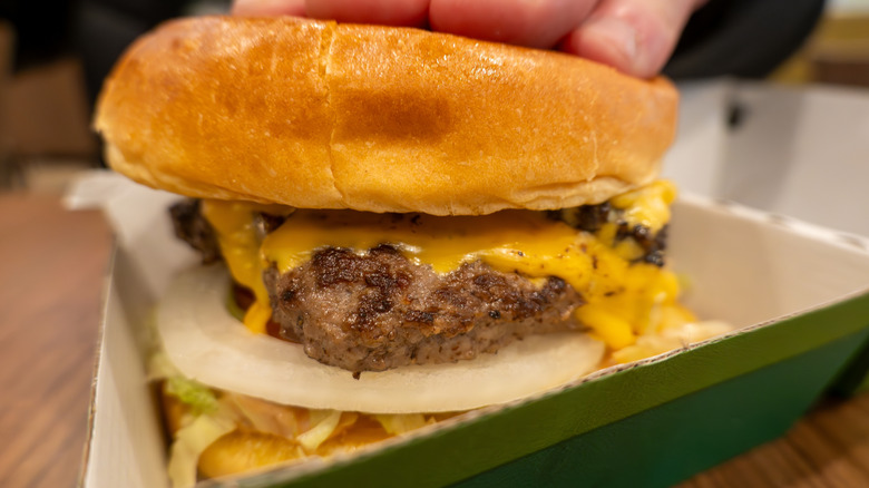 A Wahlburger burger with melted cheese and onions