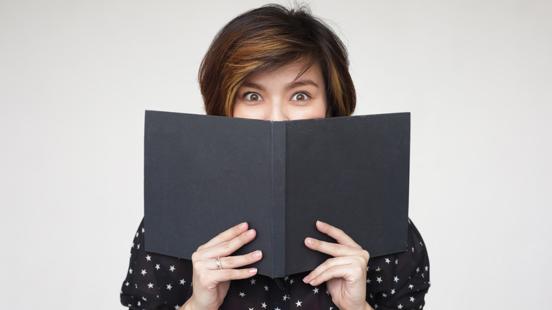 woman holding restaurant menu in front of her face