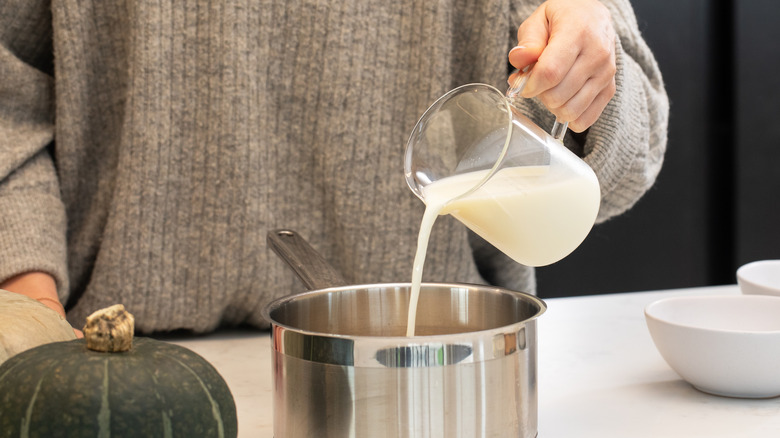 Woman pouring milk into saucepan