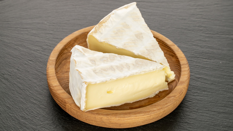 A plate with two wedges of brie cheese on it.