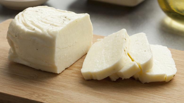 A sliced piece of Halloumi on a wooden cutting board.