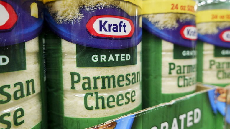 A grocery store aisle filled with bottles of Kraft pre-grated Parmesan Cheese.