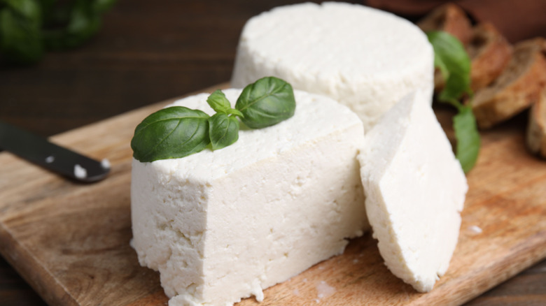 Two wheels of Ricotta cheese sliced on a wooden cutting board.