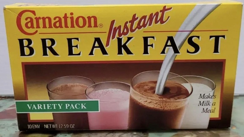 A vintage box of Carnation Instant Breakfast envelopes; box is yellow and depicts a photo of four glasses of milk; logo is in red and black