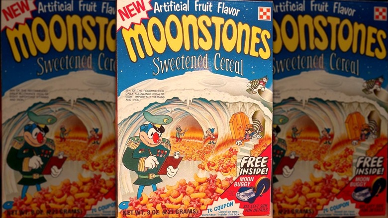 A box of Monstones cereal; logo is yellow on a blue background; cartoon drawing of a moons scene with a military-like figure with a clipboard  and other figures scattered around moon- and star-shaped cereal
