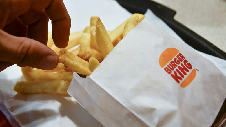 Hand grabbing a fry from a Burger King fry packet