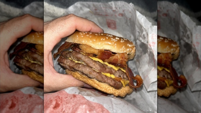 A hand holding a Bacon King, Rodeo style burger