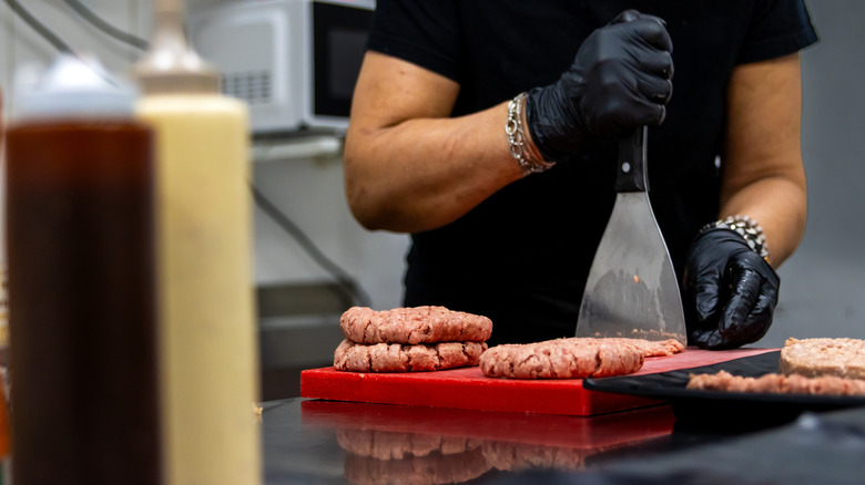 A chef preparing burger patties