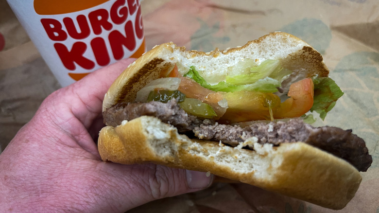 Hand holding a half-eaten Burger King burger