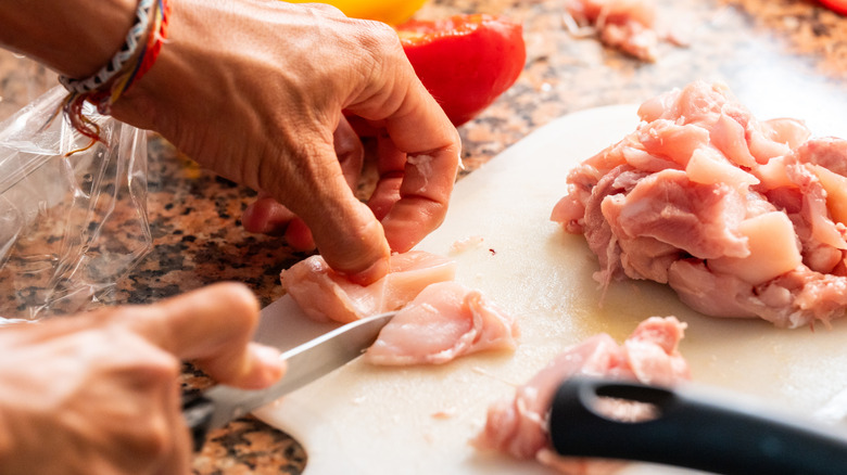 Man cutting meat on a plastic board