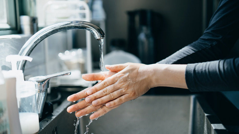 Woman washing hands in kitchen sink