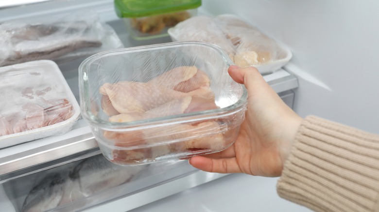 Woman placing raw chicken in the fridge
