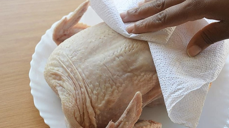 Person patting chicken dry with a paper towel