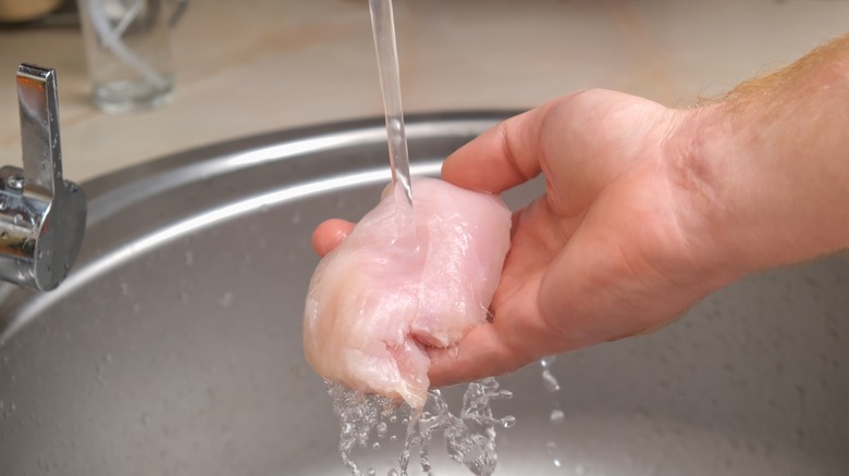 Man washing raw chicken