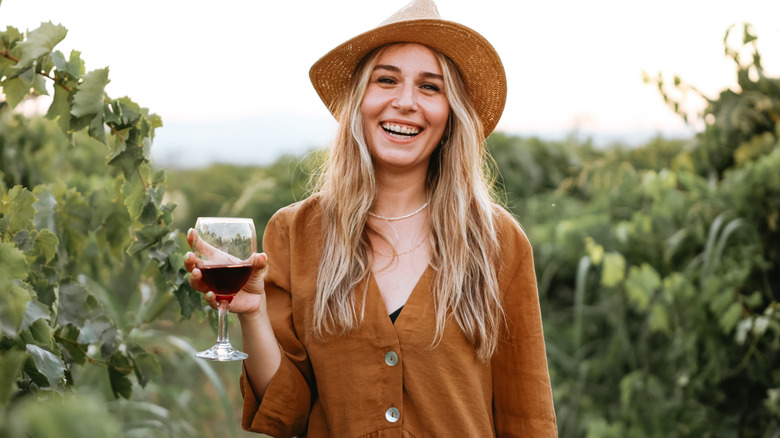 Woman in vineyard holding wine glass incorrectly