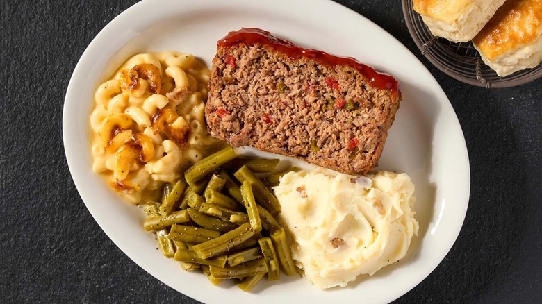 Cracker Barrel meatloaf on a plate with mashed potatoes, mac and cheese, and green beans