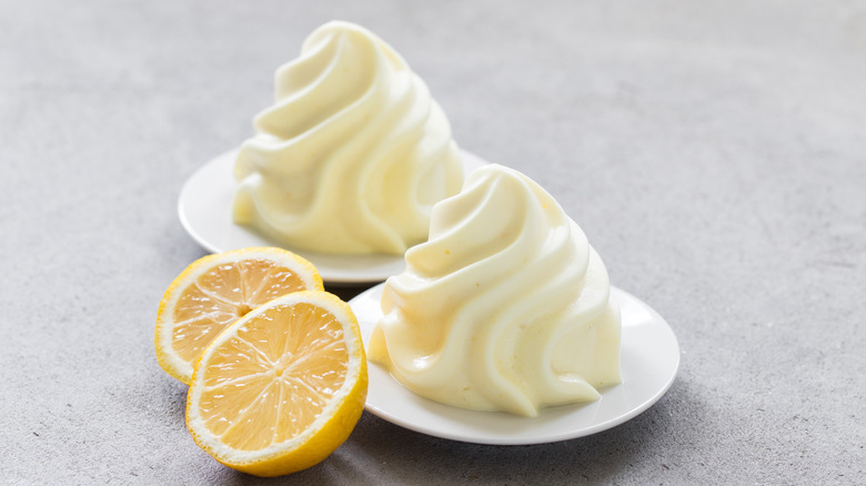 Two small bowls of whipped cream with half of lemon next to them