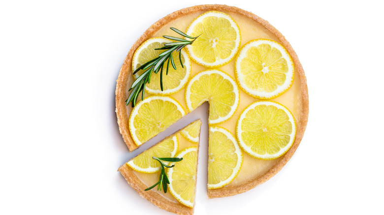 Traditional french lemon tart with rosemary leaves isolated on white